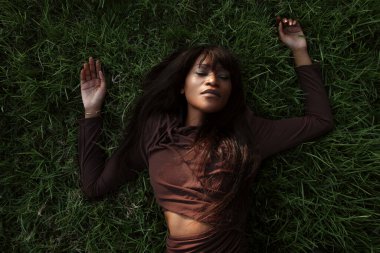 Çekici, güzel ve Afro-Amerikalı bir kadın. Açık havada kahverengi elbise giymiş poz veriyor. - Evet. Yüksek kalite fotoğraf.