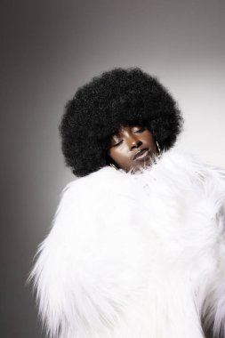 Beyaz arka planda afro saçlı şık Afrikalı Amerikalı genç bir kadın. Dikey. Yüksek kalite fotoğraf.