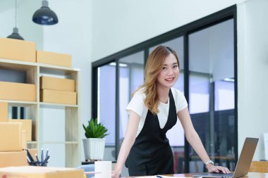 Çevrimiçi pazarlama paketi ve KOBİ teslimat kavramının neşeli başarısı ile bilgisayar laptopu kullanarak gülümseyen bağımsız Asyalı kadının küçük işletme girişimciliğini başlatan.