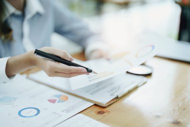 Düşünceli bir Asyalı iş kadınının portresi finansal tablolara bakıyor ve masasındaki bilgisayarı kullanarak pazarlama planları yapıyor..