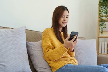 Evdeki koltukta oturan kadın cep telefonunu kullanmaya hazır..