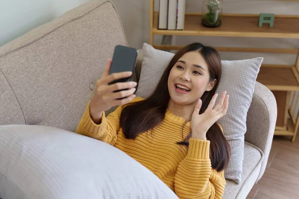 一个女人躺在沙发上用她的电话和她的朋友们视频聊天 — 图库照片