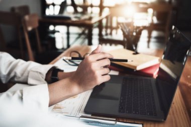 Kalem tutan ve bilgisayarla şirketin yatırım bütçesini kontrol eden bir kadın işçi.