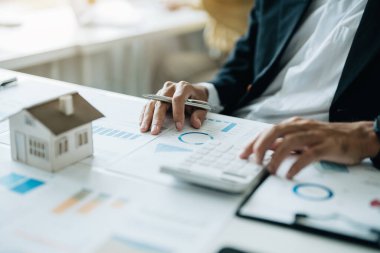 Banka kredi çalışanları, müşterilerin iş yerlerindeki kilit belgeleri kullanarak yatırım becerilerini değerlendirmeleri için ev kredisi faiz oranlarını hesaplamak için hesap makineleri kullanıyorlar..