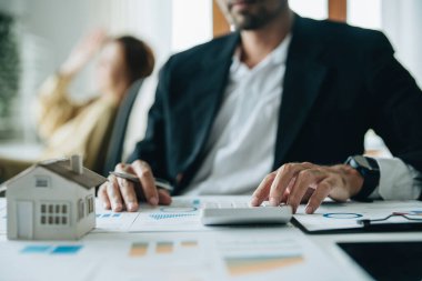 Banka kredi çalışanları, müşterilerin iş yerlerindeki kilit belgeleri kullanarak yatırım becerilerini değerlendirmeleri için ev kredisi faiz oranlarını hesaplamak için hesap makineleri kullanıyorlar..