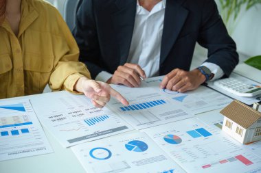 Kredi departmanındaki bir banka memuru, gayrimenkul yatırımlarının risklerini değerlendirmek amacıyla müşterilere ev kredilerinin faiz oranlarını açıklar