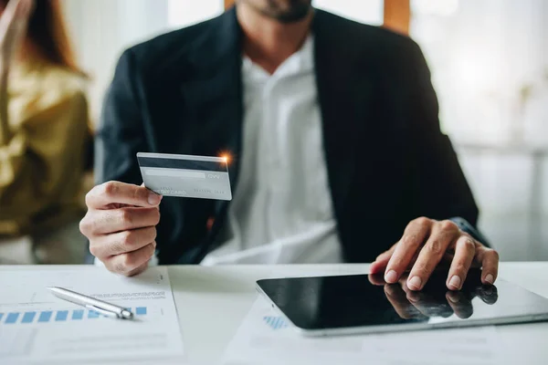 stock image online payment and shopping, a male businessman uses a credit card to swipe for a discount using a tablet to select products.