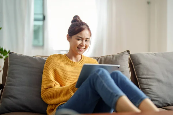 一个年轻的亚洲女人在沙发上使用平板电脑的肖像 — 图库照片