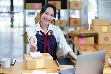 Çevrimiçi pazarlama paketi ve KOBİ teslimat kavramının neşeli başarısı ile bilgisayar laptopu kullanarak gülümseyen bağımsız Asyalı kadının küçük işletme girişimciliğini başlatan.