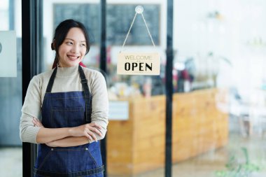 Küçük bir işletme kuran ve açan genç bir Asyalı kadın, kafeterya tezgahının önünde duran önlüklü gülen bir yüz gösteriyor. İş sahibi, Restoran, Barista, Cafe, Çevrimiçi KOBİ.