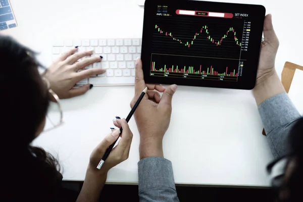 投資の専門家は 利益を上げる方法を教えるために株式市場を分析するためにタブレットモニターでペンを指す — ストック写真