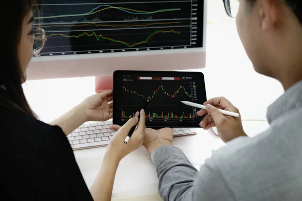 投資の専門家は 利益を上げる方法を教えるために株式市場を分析するためにタブレットモニターでペンを指す — ストック写真