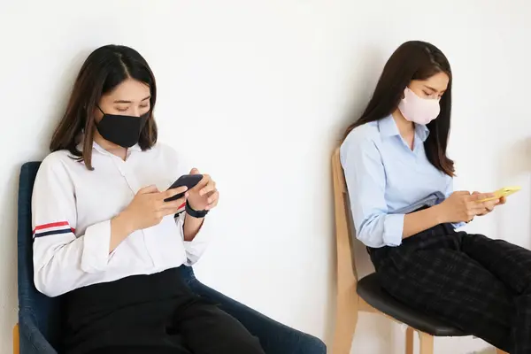 Koncepcja Dystansu Społecznego Dwie Kobiety Maskach Dystans Podczas Siedzenia Telefonach — Zdjęcie stockowe