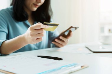 İnternetten alışveriş için kredi kartı ve telefon kullanan Asyalı genç bir kadının portresi..