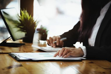 İş kadını belge bütçesine işaret ediyor ve hesaplama bütçesine yıllık bilançoyu gözden geçirmek için hesap makinesi kullanıyor. Yatırımdan önce denetim bütünlüğü
