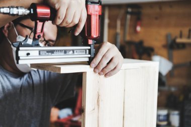 Entrepreneur Woodwork holding a Tacker to assemble the wood pieces as the customer ordered