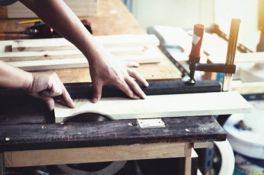 Woodworking practitioners use saw blades to cut wood pieces to assemble and build wooden tables for their clients