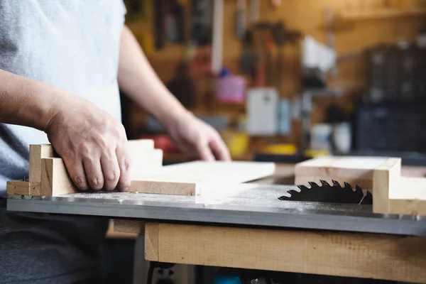 Woodworking practitioners use saw blades to cut wood pieces to assemble and build wooden tables for their clients