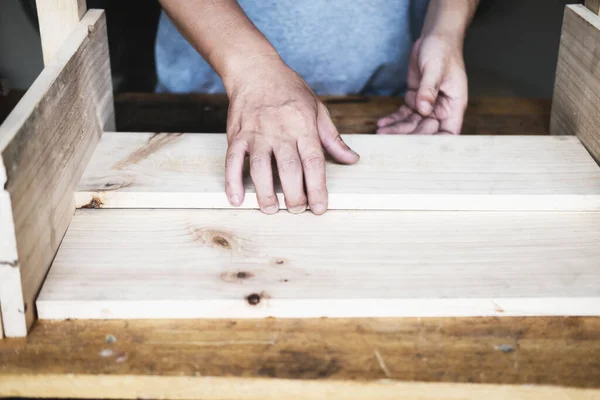 stock image A carpenter measures the planks to assemble the parts, and build a wooden table for the customer