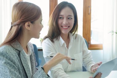 Genç Asyalı iş kadını pazarlama stratejileri planlamak için tablet bilgisayar kullanıyor ve müşterilerden kâr elde etmek için yatırım yapıyor.