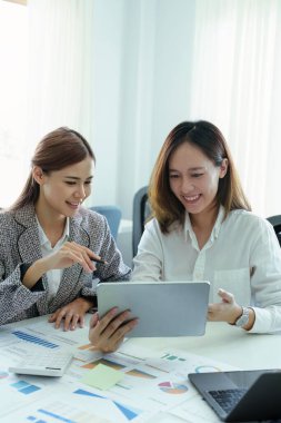 Genç Asyalı iş kadını pazarlama stratejileri planlamak için tablet bilgisayar kullanıyor ve müşterilerden kâr elde etmek için yatırım yapıyor.