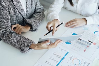 Genç Asyalı iş kadını pazarlama stratejileri planlamak için tablet bilgisayar kullanıyor ve müşterilerden kâr elde etmek için yatırım yapıyor.