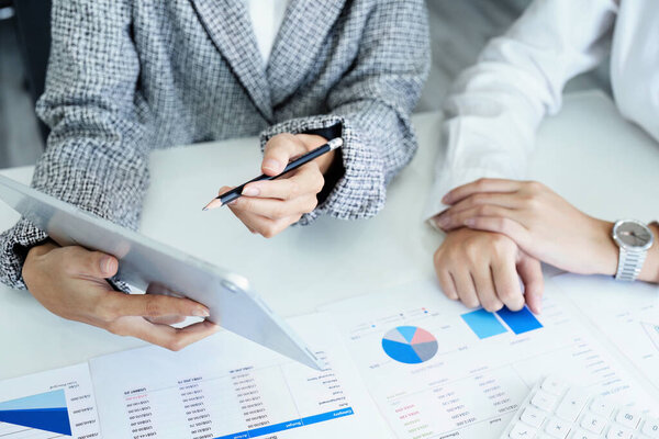 молодая азиатская предпринимательница, использующая планшетные компьютеры для планирования маркетинговых стратегий и инвестирования в прибыль от клиентов.