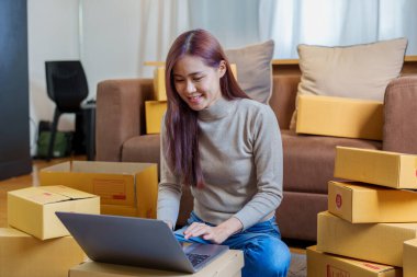 A portrait of a small startup, an SME owner, an Asian female entrepreneur checking orders to arrange the produce before packing the products in the inner boxes with the customers. Freelance concepts.