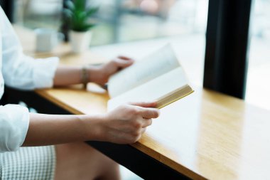 Yemek arasında kitap okuyan güzel bir Asyalı kadın çalışanın portresi..