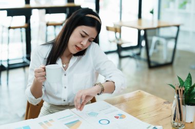 Güzel bir Asyalı çalışanın portresi. Saate bakıp telefonda konuşurken koşuyor..
