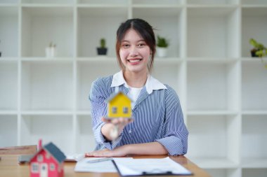 Muhasebeci, iş kadını, emlakçı, Asyalı iş kadını model ev ve anahtarları müşterilere teslim eden müşterilerin imzalaması için ev faizi hesaplama belgeleri..
