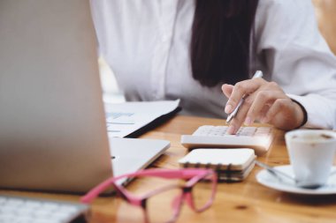 İş kadını, hesap makinesini kullanarak yıllık bilançoları gözden geçiriyor. Bütçe hesaplamak için belge ve dizüstü bilgisayar kullanıyor. Yatırım kavramından önce denetim ve denetim bütünlüğü