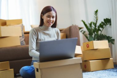 A portrait of a small startup, an SME owner, an Asian female entrepreneur checking orders to arrange the produce before packing the products in the inner boxes with the customers. Freelance concepts.