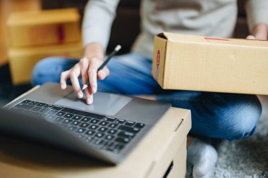 Küçük bir girişimin portresi, bir KME sahibi, bir Asyalı bayan girişimci ürünleri müşterilerle birlikte iç kutulara koymadan önce ürünleri düzenlemek için siparişleri kontrol ediyor. Serbest kavramlar.