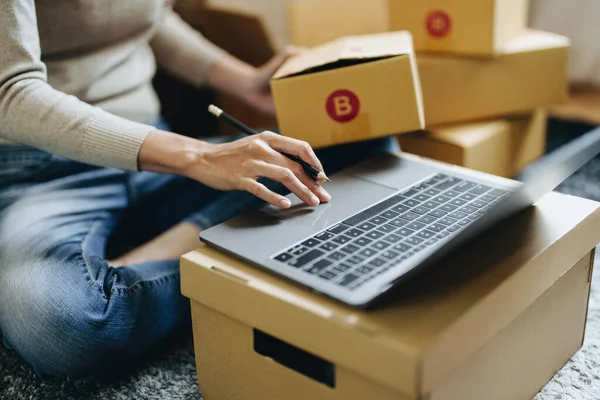 Küçük bir girişimin portresi, bir KME sahibi, bir Asyalı bayan girişimci ürünleri müşterilerle birlikte iç kutulara koymadan önce ürünleri düzenlemek için siparişleri kontrol ediyor. Serbest kavramlar.