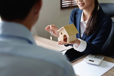 Bir emlakçının portresi kontratı imzaladıktan sonra bir çift için anahtarlı bir ev modelliği yapıyor..