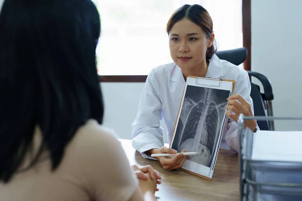 一位亚洲女医生用一部病人X光片来解释病人的治疗过程 — 图库照片