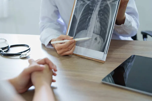 一位亚洲女医生用一部病人X光片来解释病人的治疗过程 — 图库照片