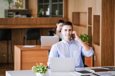 Erkek pazarlama müdürü, kâr potansiyelini artırmak için risk sermayesi şirketiyle konuşmak için telefonu kullanıyor.