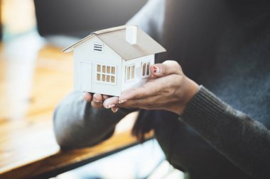 Ev modeli, sigorta konsepti ve ev kredisi tutan kadın.