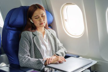 Başarılı Asyalı iş kadını portresi ya da birinci sınıf bir uçakta resmi bir takım elbise giymiş girişimci. Uçuş sırasında dinleniyor..