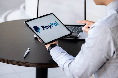 CHIANG MAI, THAILAND - 28 NOV 2021: PayPal uygulamalarıyla el ele tutuşan adam ekranda. PayPal bir çevrimiçi elektronik ödeme sistemidir.
