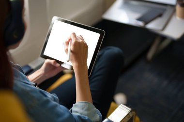 Ekonomi sınıfında Asya 'lı bir kadın uçarken mesaj ya da reklam kullanabilen beyaz ekran tableti kullanarak pencere kenarında oturuyor. Seyahat, tatil, tatil fikirleri.