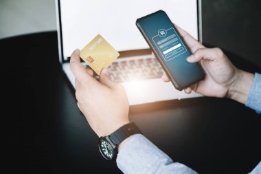 Çevrimiçi Alışveriş ve İnternet Ödemeleri, Asyalı adam internet üzerinden alışveriş yapmak veya dijital dünyada ayak işleri yapmak için kredi kartı ve cep telefonlarını kullanıyor