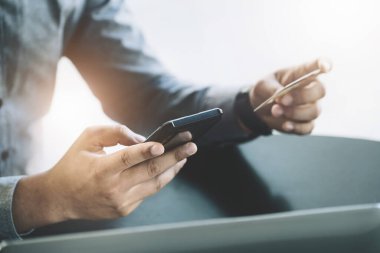 Çevrimiçi Alışveriş ve İnternet Ödemeleri, Asyalı adam internet üzerinden alışveriş yapmak veya dijital dünyada ayak işleri yapmak için cep telefonlarını ve kredi kartlarını kullanıyor