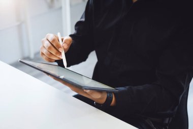 Bir erkek çalışan internet üzerinden satın alma ya da araştırma bilgileri almak için bir tablet bilgisayara kalem doğrultuyor