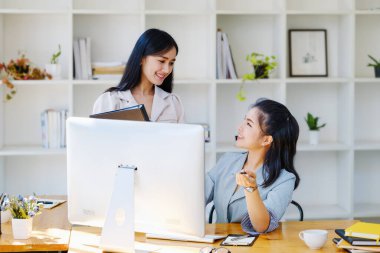 Danışmanlık, tartışma, pazarlama ve yatırım konsepti, bilgisayar monitörünü işaret eden kadın çalışan ve şirket için yatırım risklerini değerlendirmek için elinde klasör tutan iş arkadaşı