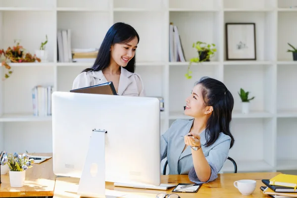 营销和投资概念 女员工指着电脑显示器和同事文件夹 为公司得出结论和评估投资风险 — 图库照片