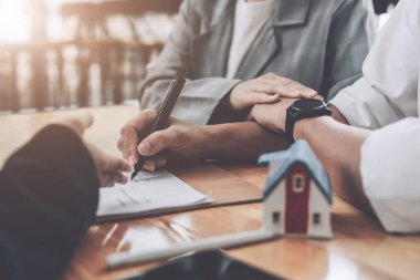 Ev sözleşmesine giren bir eş, banka memurunun veya emlakçının imzalamadan önce önerdiği kredi faiz anlaşmasının şartlarını okumaktadır..