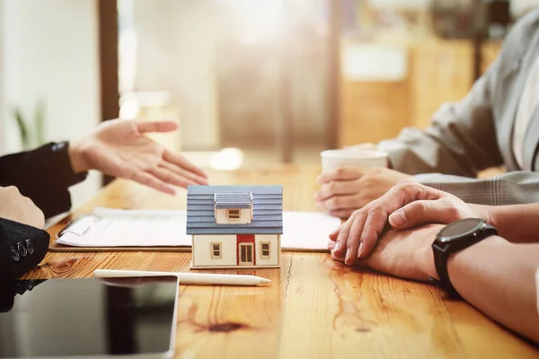A spouse entering a home contract is reading the terms of the loan interest agreement that the bank officer or real estate agent is offering before signing.